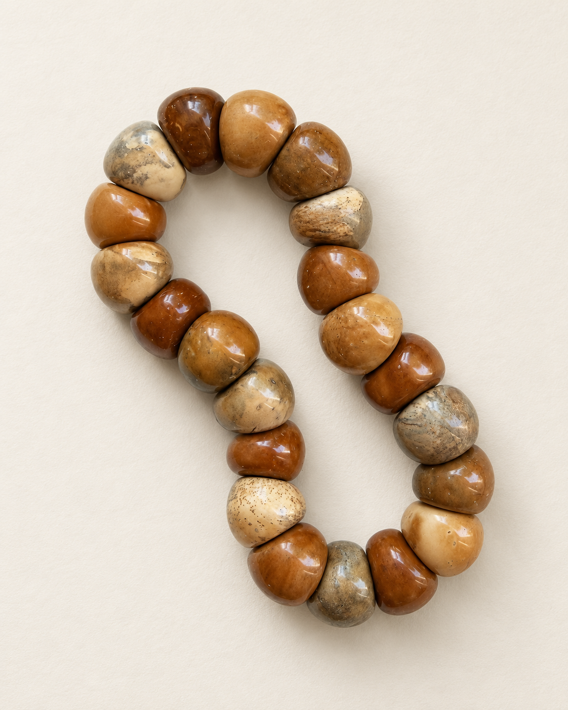 Kuke bracelet with irregular swirl-pattern beads on a warm ivory surface