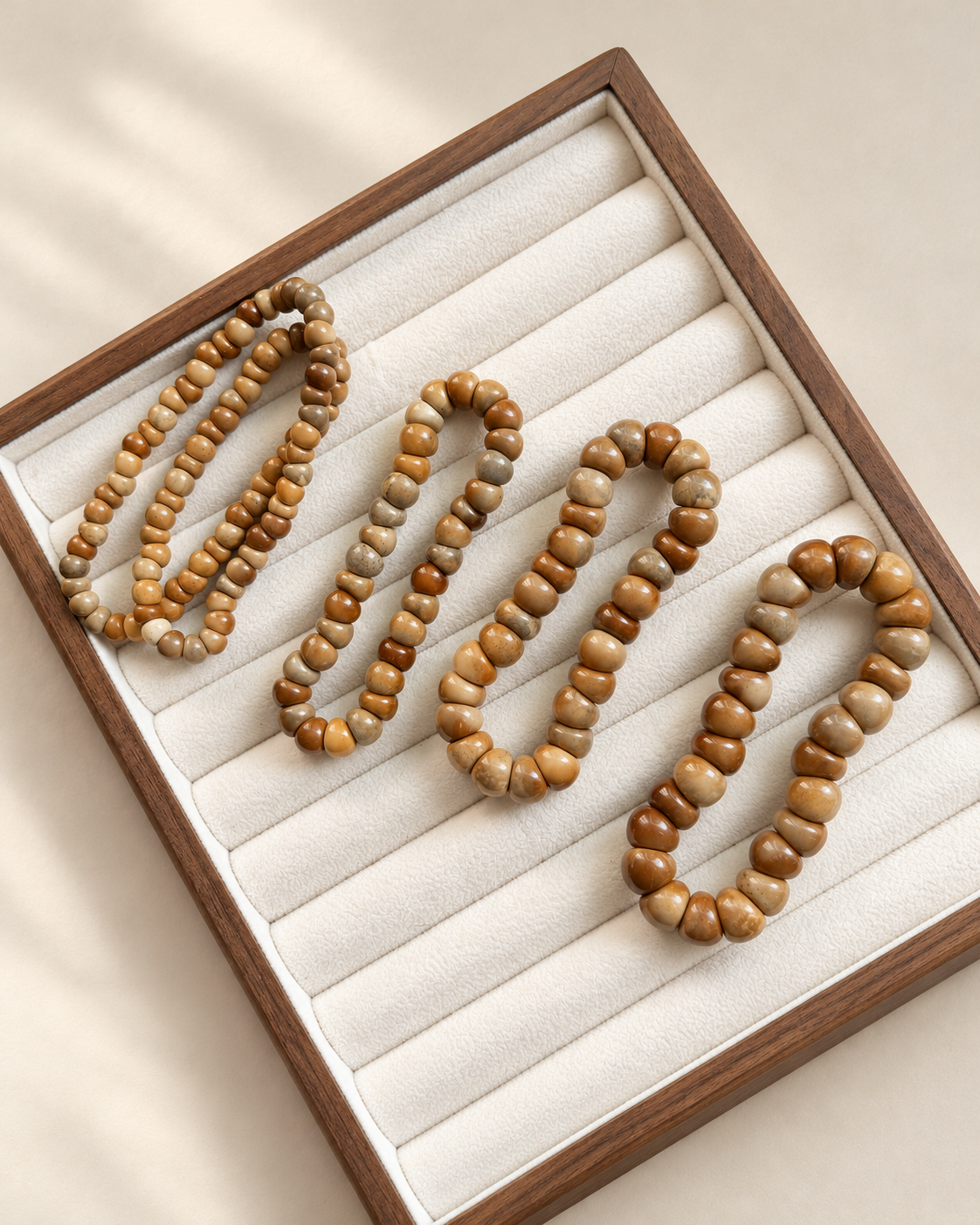 Kuke bracelets in varying bead sizes arranged on an ivory-lined tray