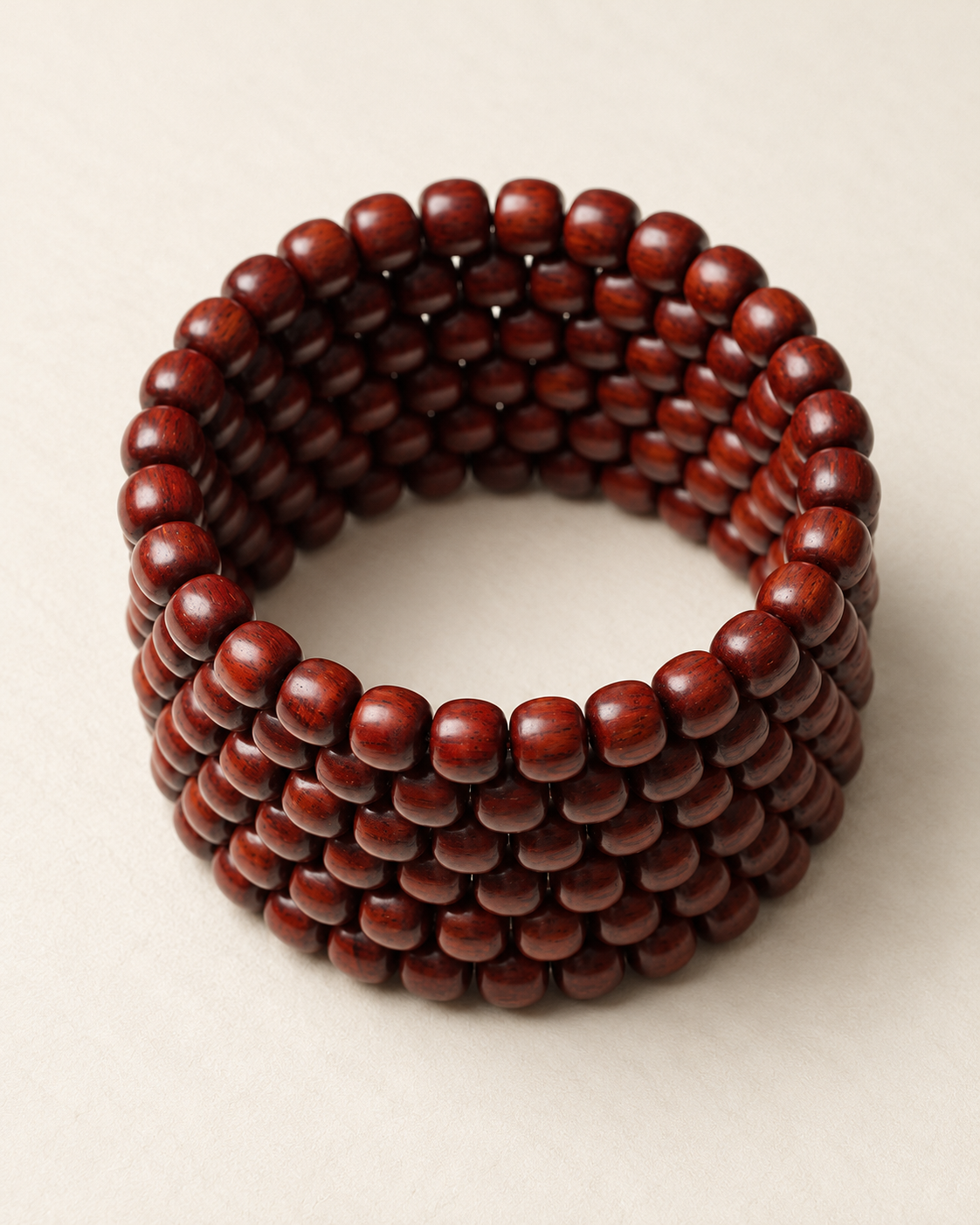 Coiled strand of 8 mm zitan beads on an ivory surface