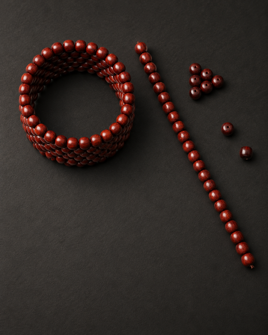 Coiled zitan strand, straight strand and loose beads on a charcoal surface