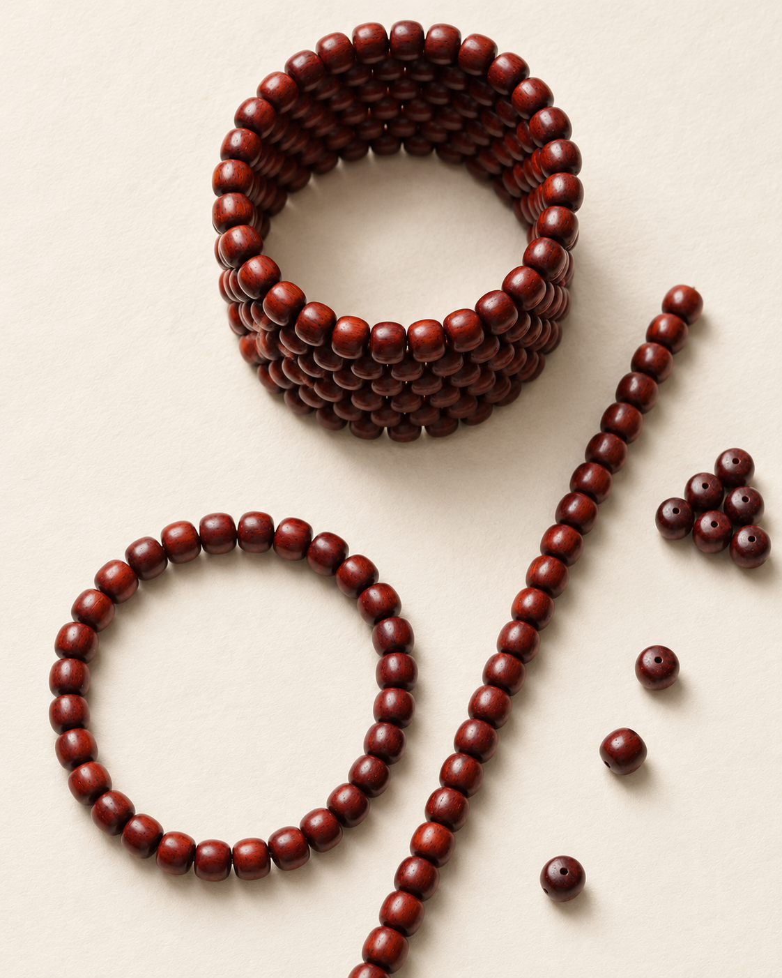 Zitan bead coil, bracelet and straight strand on an ivory surface